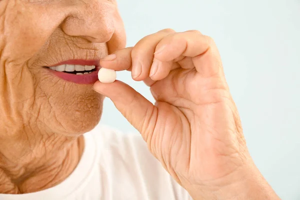 Elderly woman taking pill on light background, closeup Royalty Free Stock Images