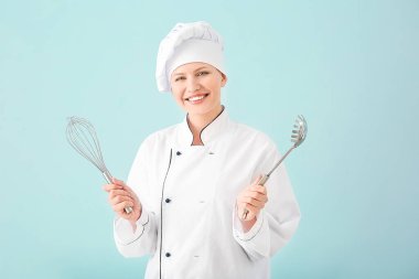 Arka planda mutfak gereçleri olan güzel bir kadın şef.