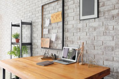 Tuğla duvarın yanında ruh hali ve dizüstü bilgisayarı olan rahat bir iş yeri