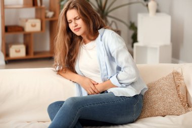 Evde karın ağrısı çeken genç bir kadın var.