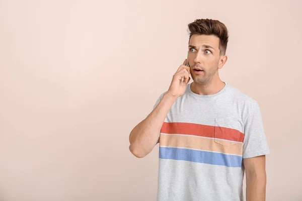 Σοκαρισμένος νεαρός μιλώντας από το τηλέφωνο στο φόντο χρώμα — Φωτογραφία Αρχείου