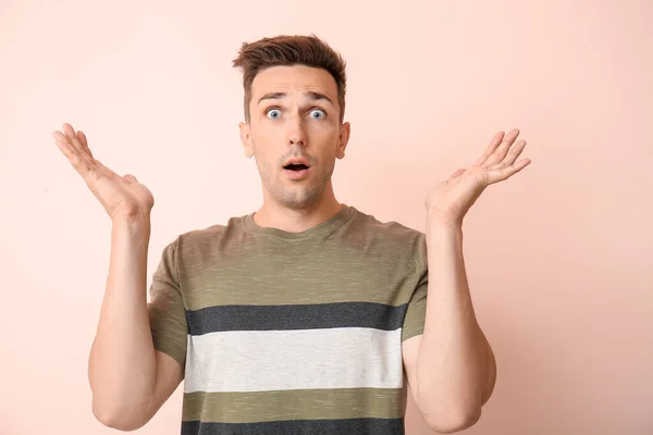Shocked young man on color background — Stock Photo, Image