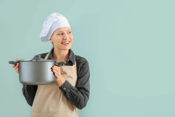 Mooie vrouwelijke chef met steelpan op kleur achtergrond — Stockfoto