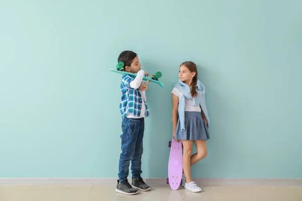 Roztomilé módní děti s skateboardy poblíž barevné stěny — Stock fotografie