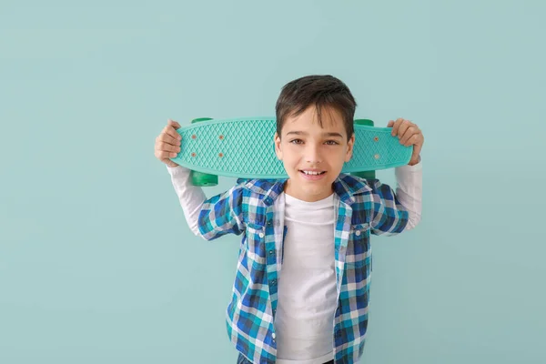 Carino ragazzo alla moda con skateboard su sfondo di colore — Foto Stock