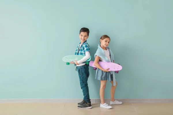 Roztomilé módní děti s skateboardy poblíž barevné stěny — Stock fotografie