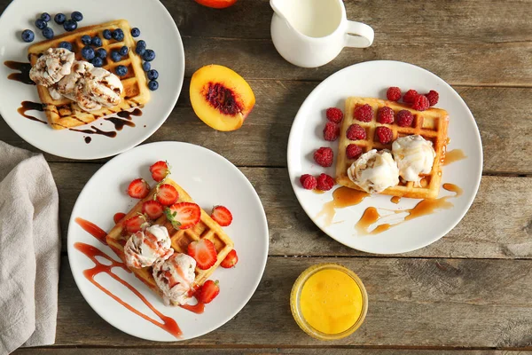 Plates with tasty waffles, berries and ice cream on table — Stock Photo, Image