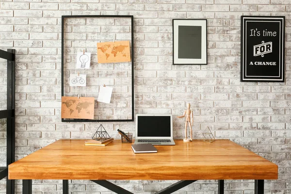 Comfortable workplace with mood board and laptop near brick wall — Stock Photo, Image