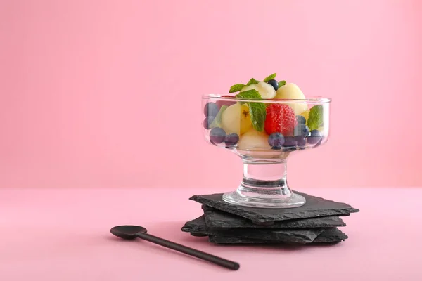 Schüssel mit leckerem Obstsalat auf farbigem Hintergrund — Stockfoto