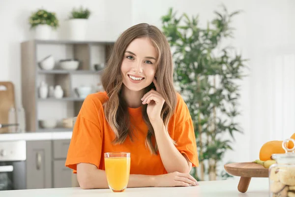 Belle jeune femme buvant du jus d'orange dans la cuisine — Photo