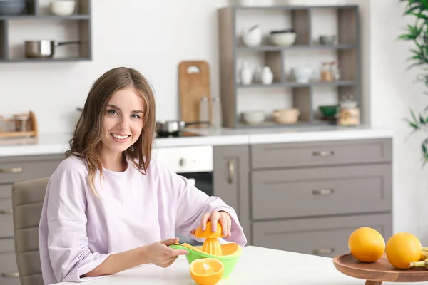 Mulher bonita fazendo suco de laranja fresco na cozinha — Fotografia de Stock