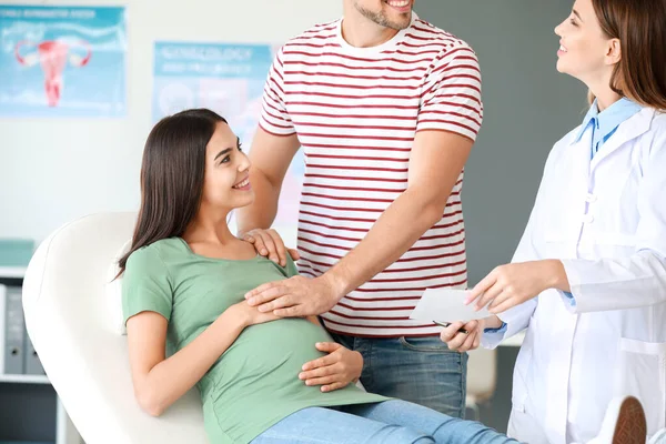 Pareja embarazada visitando ginecóloga femenina en clínica —  Fotos de Stock