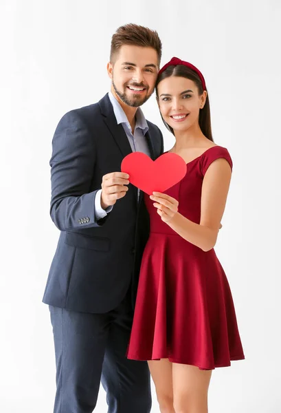Portrait of beautiful young couple with paper heart on white background — Stock Photo, Image