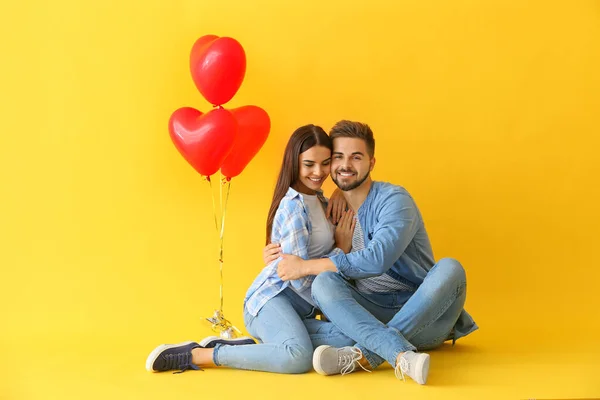 Portrait of beautiful young couple with air balloons on color background — Stock Photo, Image