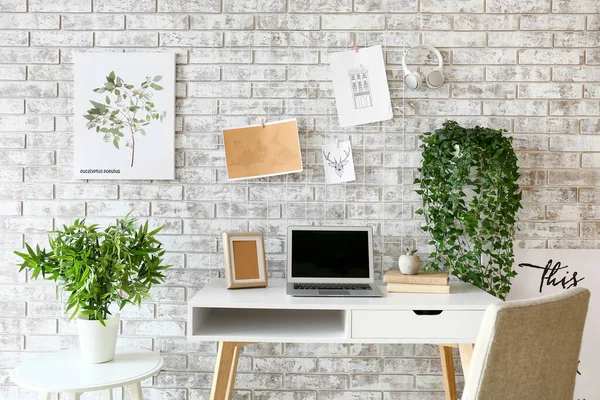 Komfortabler Arbeitsplatz mit Mood Board und Laptop in der Nähe der Ziegelwand — Stockfoto