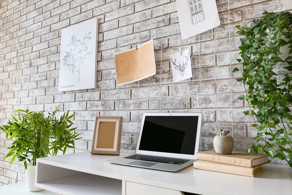 在砖墙附近有舒适的工作环境，有情绪板和笔记本电脑 — 图库照片