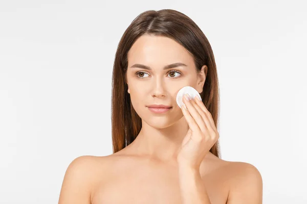 Beautiful young woman using cotton pad for makeup removal on light background — Stock Photo, Image