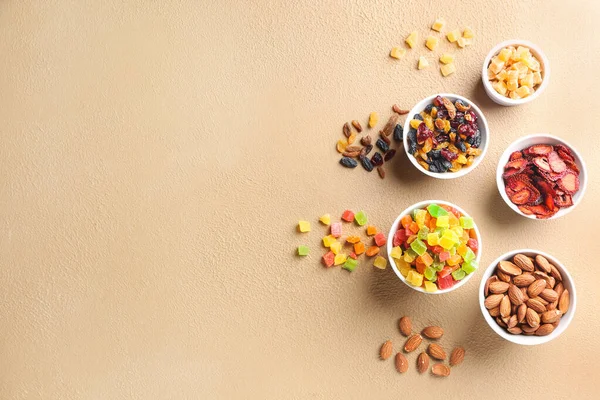 Cuencos con diferentes frutos secos y frutos secos sobre fondo de color — Foto de Stock
