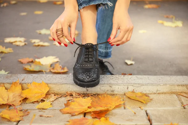 Красива молода жінка зав'язує шнурки на міській вулиці в осінній день — стокове фото