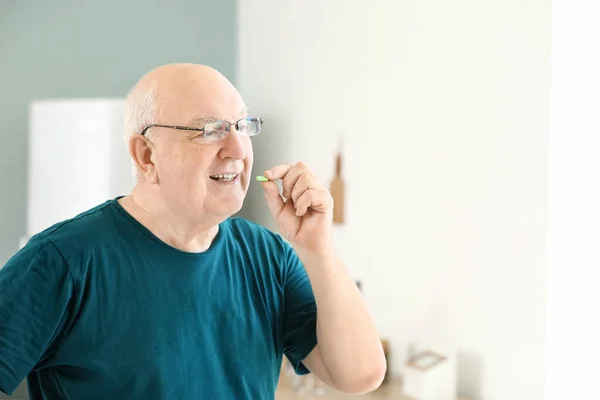 Elderly man taking medicine at home — Stock Photo, Image