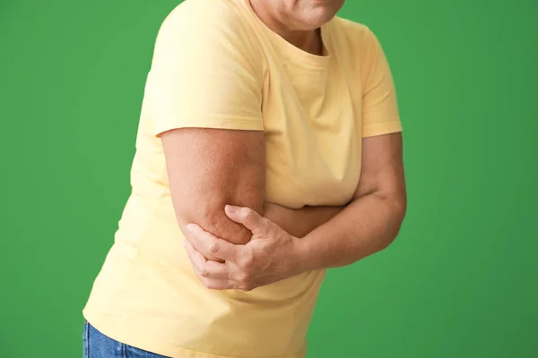 Volwassen vrouw die lijden aan pijn in elleboog op kleur achtergrond — Stockfoto