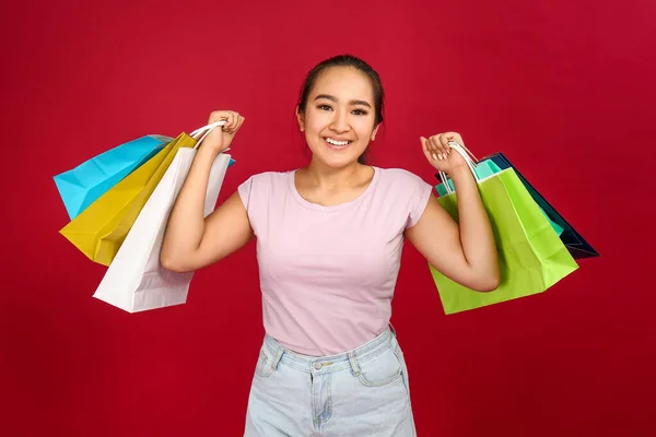 Portret van een gelukkige Aziatische vrouw met boodschappentassen op kleur achtergrond — Stockfoto