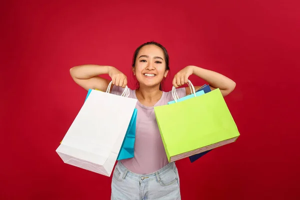 Portret van een gelukkige Aziatische vrouw met boodschappentassen op kleur achtergrond — Stockfoto