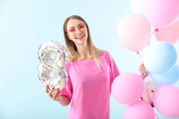 Hermosa mujer joven con figura 8 y globos de aire sobre fondo de color. Celebración del Día Internacional de la Mujer —  Fotos de Stock