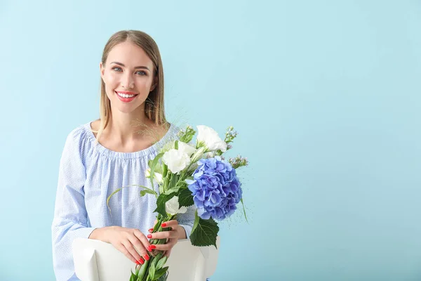 Hermosa mujer joven con flores sobre fondo de color — Foto de Stock