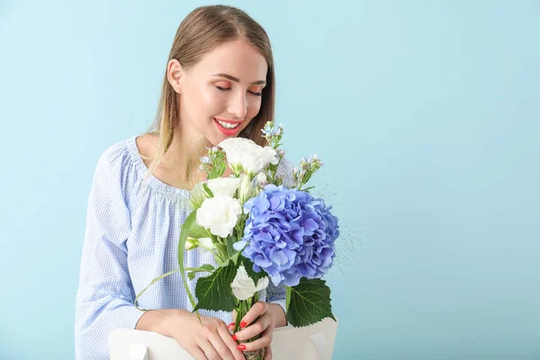 Hermosa mujer joven con flores sobre fondo de color — Foto de Stock