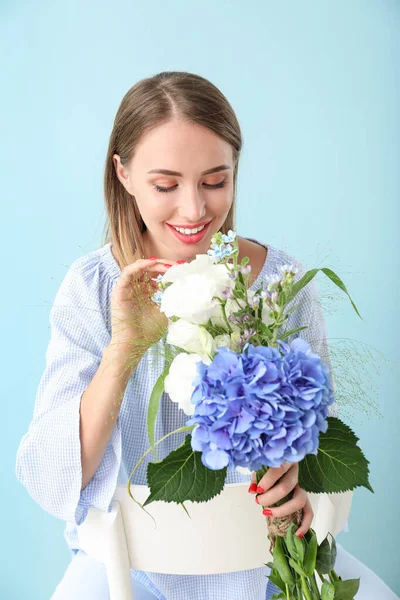 Hermosa mujer joven con flores sobre fondo de color — Foto de Stock