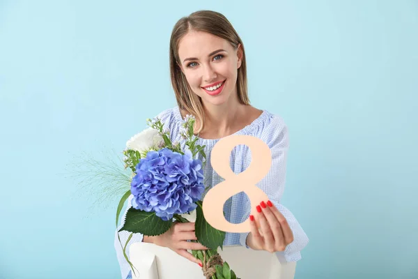Beautiful young woman with figure 8 and flowers on color background. International Women's Day celebration