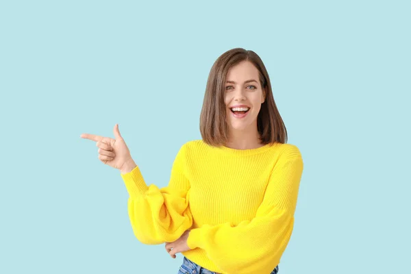 Porträtt av vackra unga kvinna som pekar på något på färg bakgrunden — Stockfoto