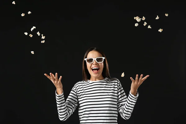 Happy woman with flying popcorn on dark background — Stock Photo, Image