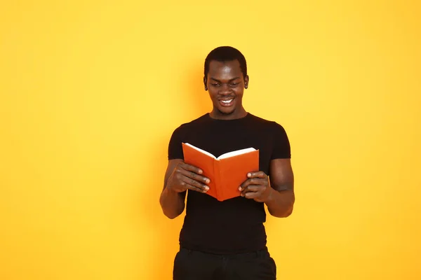 Hombre afroamericano guapo con libro sobre fondo de color — Foto de Stock