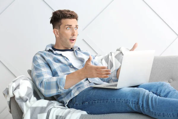 Shocked young man with laptop at home — Stock Photo, Image