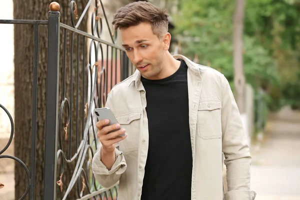 Guapo joven con teléfono móvil al aire libre —  Fotos de Stock