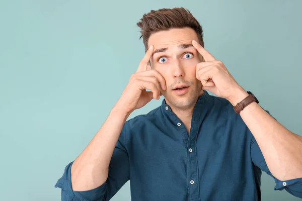 Surprised young man on color background — Stock Photo, Image