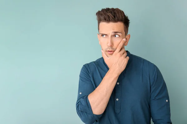 Thoughtful young man on color background — Stock Photo, Image