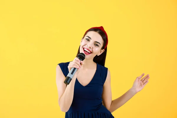 Beautiful young female singer with microphone on color background — Stock Photo, Image