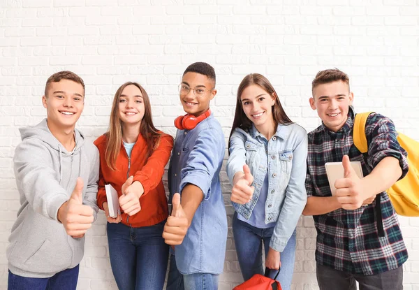 Portrait of teenagers showing thumb-up near white brick wall — Stock Photo, Image