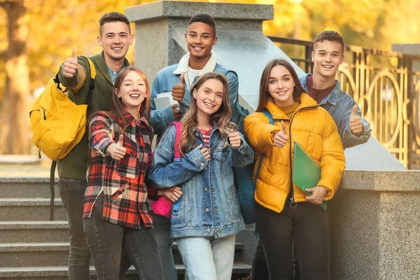 Tinédzser diákok csoportja, akik a szabadban mutogatják az ujjukat — Stock Fotó