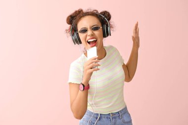 Renkli arka planda müzik dinlerken şarkı söyleyen güzel Afro-Amerikalı kadın