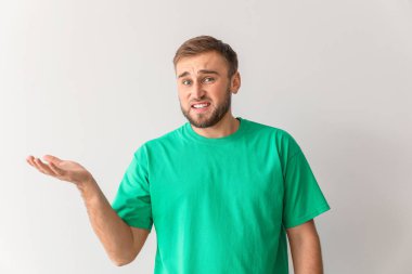 Kafası karışmış genç adam arka planda bir şeyler gösteriyor.