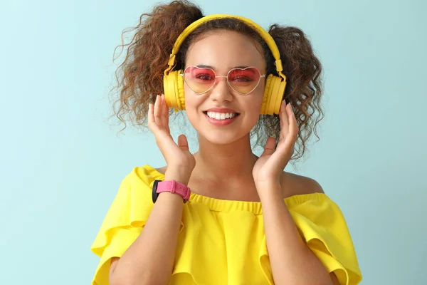 Beautiful African-American woman listening to music on color background — Stock Photo, Image