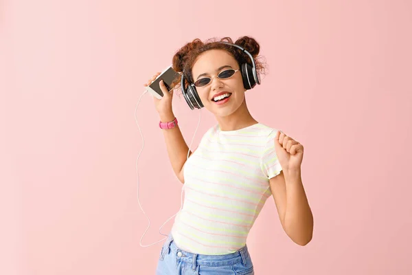 Hermosa mujer afroamericana escuchando música sobre fondo de color — Foto de Stock