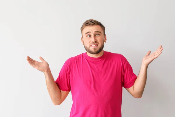 Verwirrter junger Mann vor hellem Hintergrund — Stockfoto