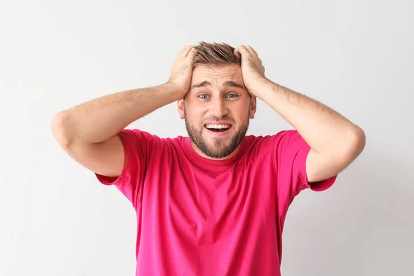 Verrast jongeman op lichte achtergrond — Stockfoto