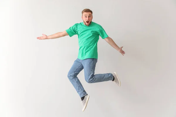 Surprised jumping young man on light background — Stock Photo, Image