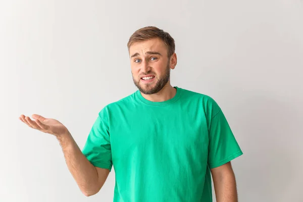 Confused young man showing something on light background — Stockfoto